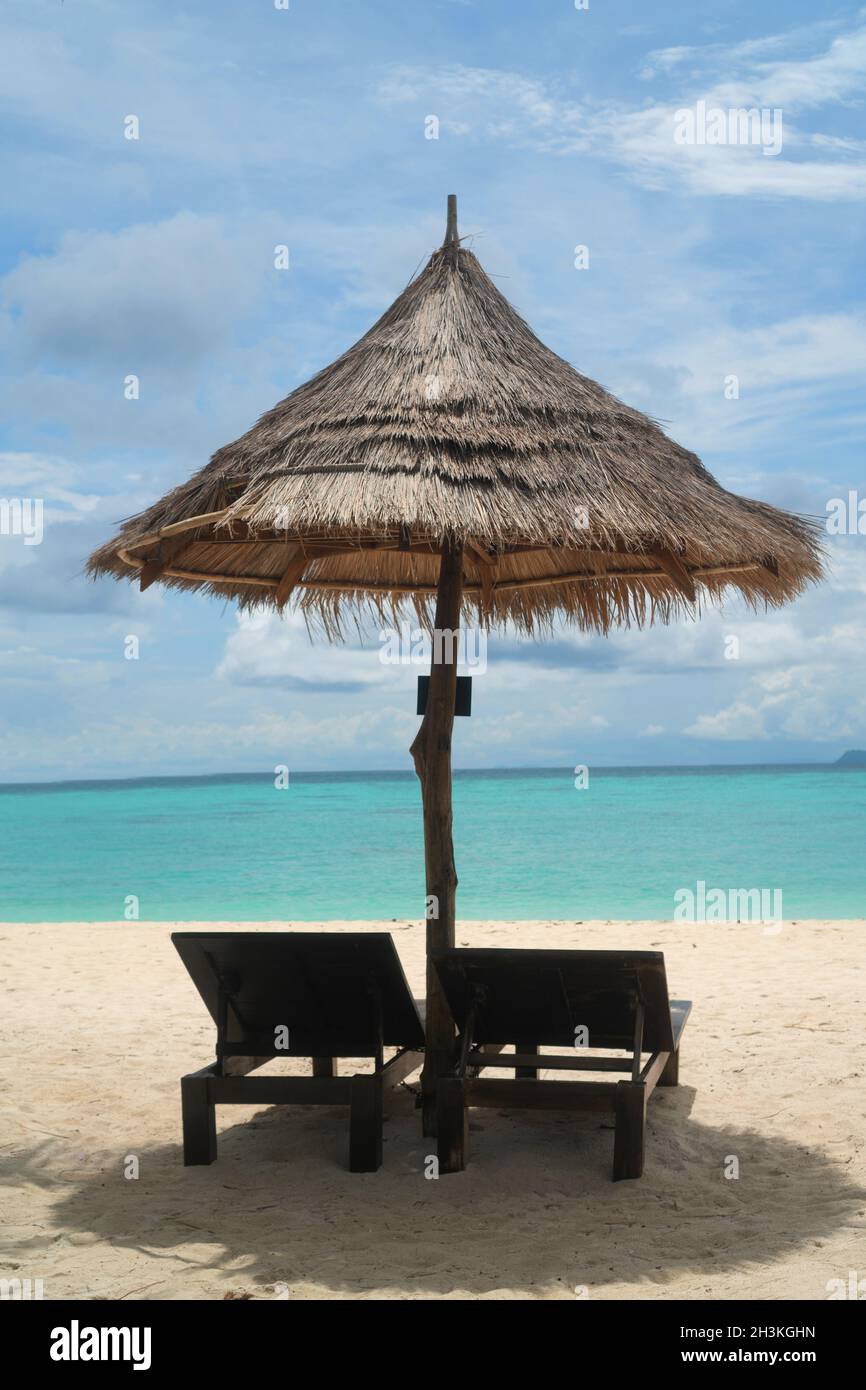 Spiaggia tropicale con sdraio e ombrellone sull'acqua di mare della laguna Foto Stock