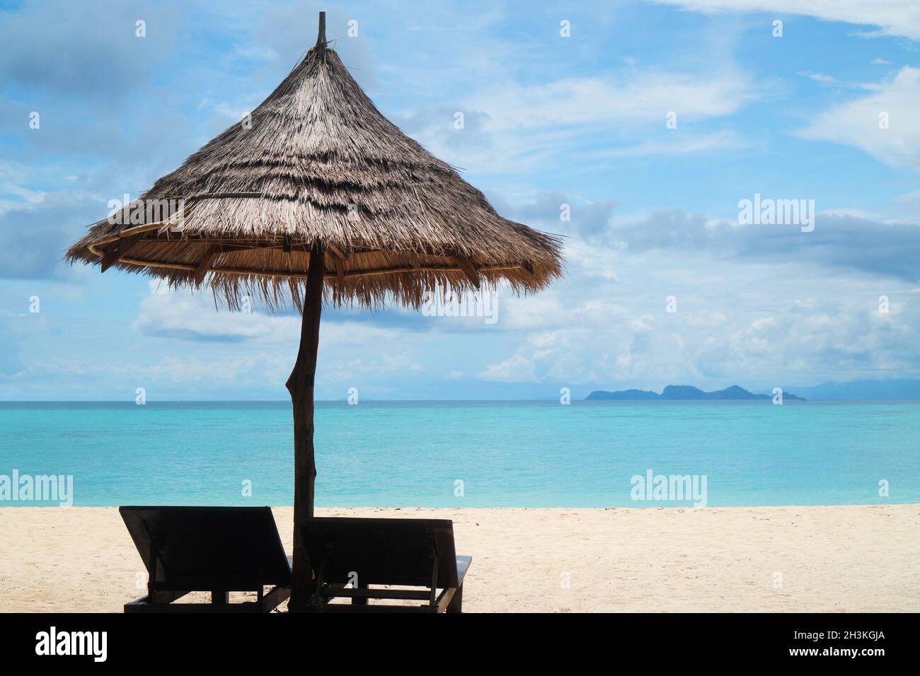 Spiaggia tropicale con sdraio e ombrellone sull'acqua di mare della laguna Foto Stock