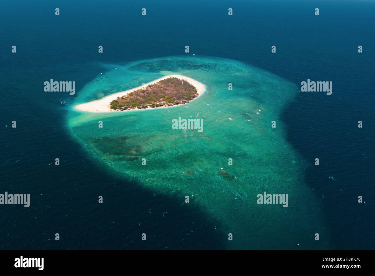 Vista aerea di una piccola isola esotica circondata dalla barriera corallina e dal mare blu Foto Stock