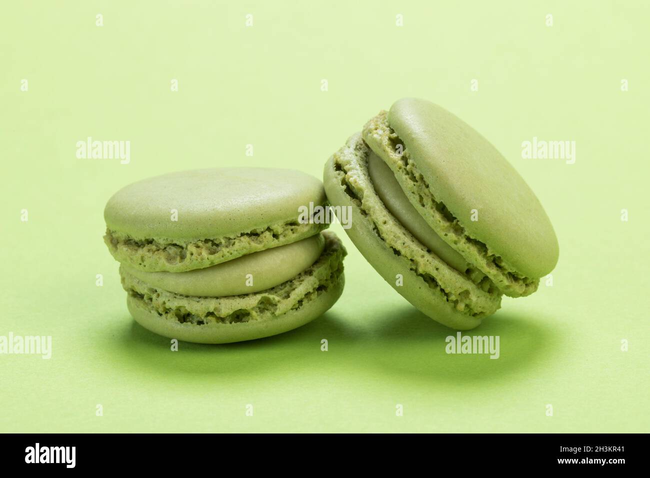 Sapore di pistacchio biscotti francesi di macaron primo piano su sfondo dello stesso colore verde pastello Foto Stock