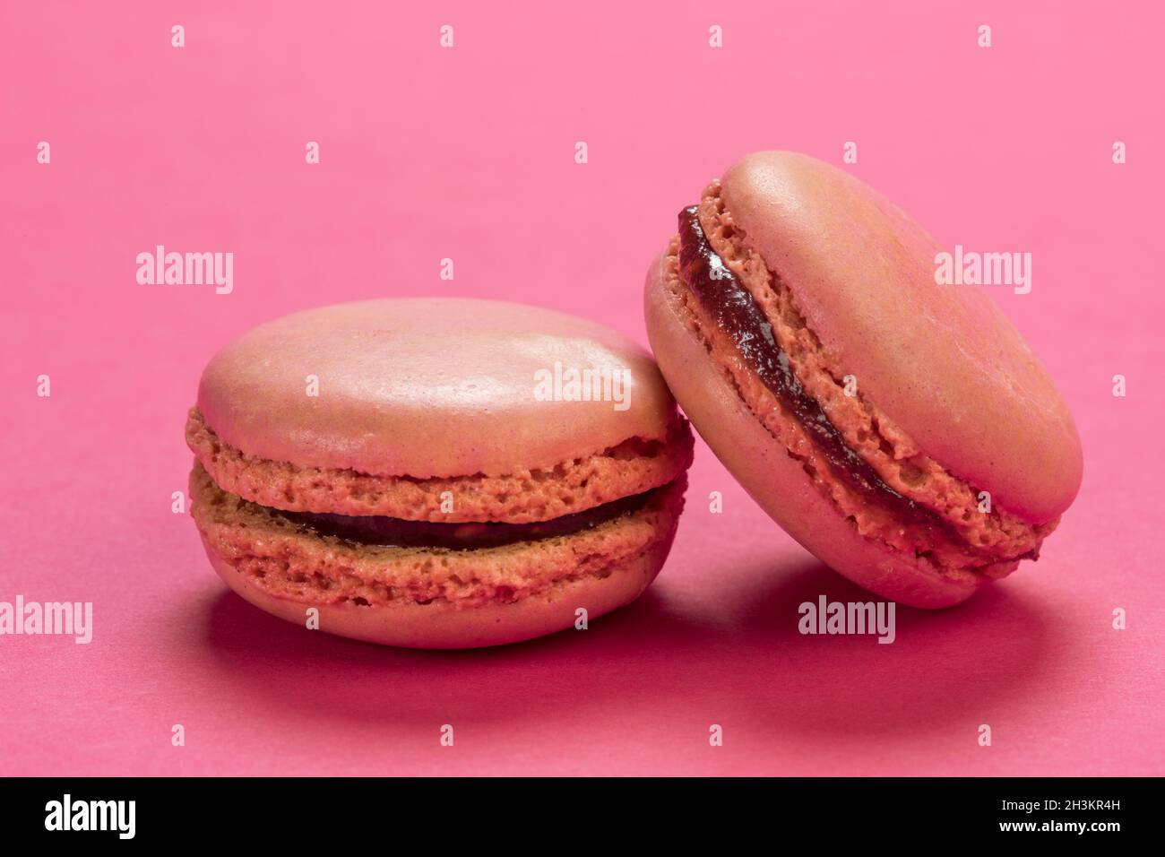 Sapore di lampone biscotti francesi di macaron da vicino su sfondo di un colore rosa pastello simile Foto Stock