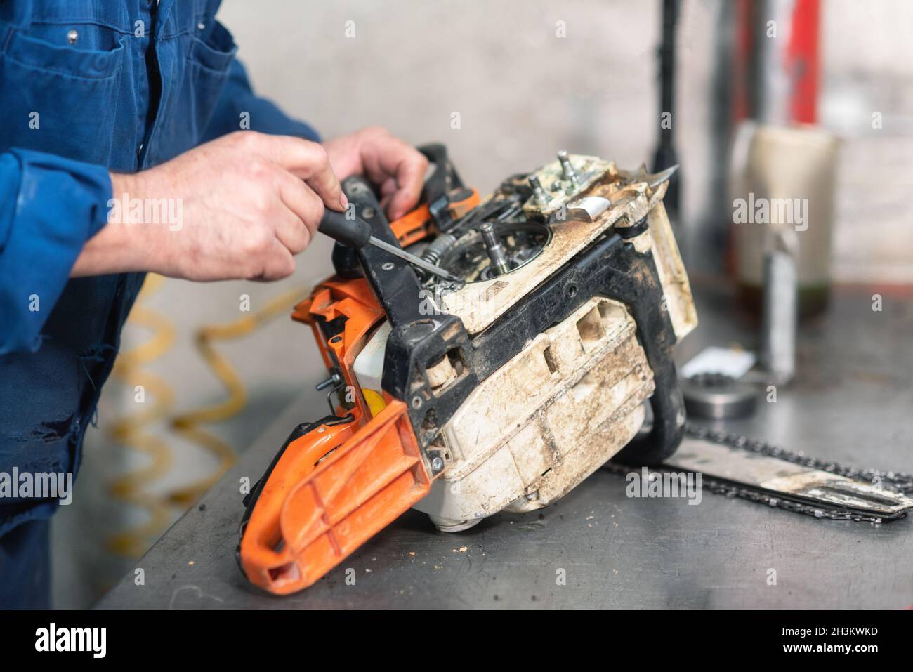Riparazione meccanica di una motosega. Uomo che ripara una motosega sul  banco da lavoro Foto stock - Alamy