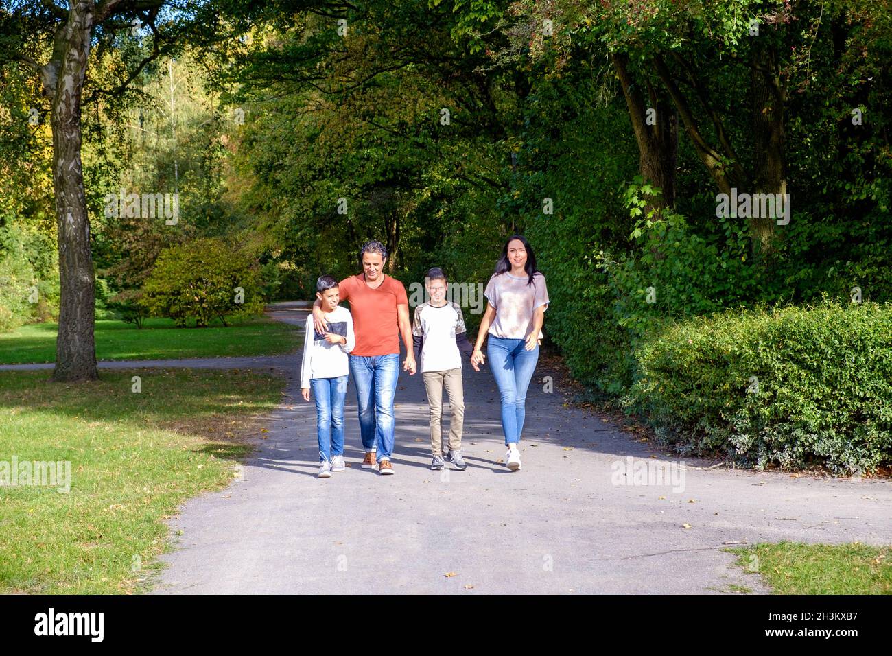 Famiglia a piedi con due bambini nel parco Foto Stock