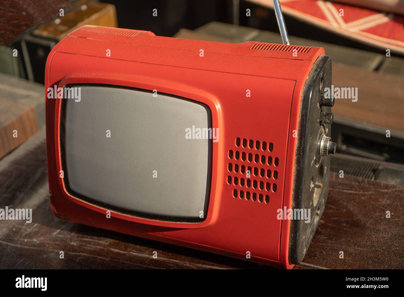 Il vecchio televisore rosso retrò si trova su un tavolo di legno Foto Stock