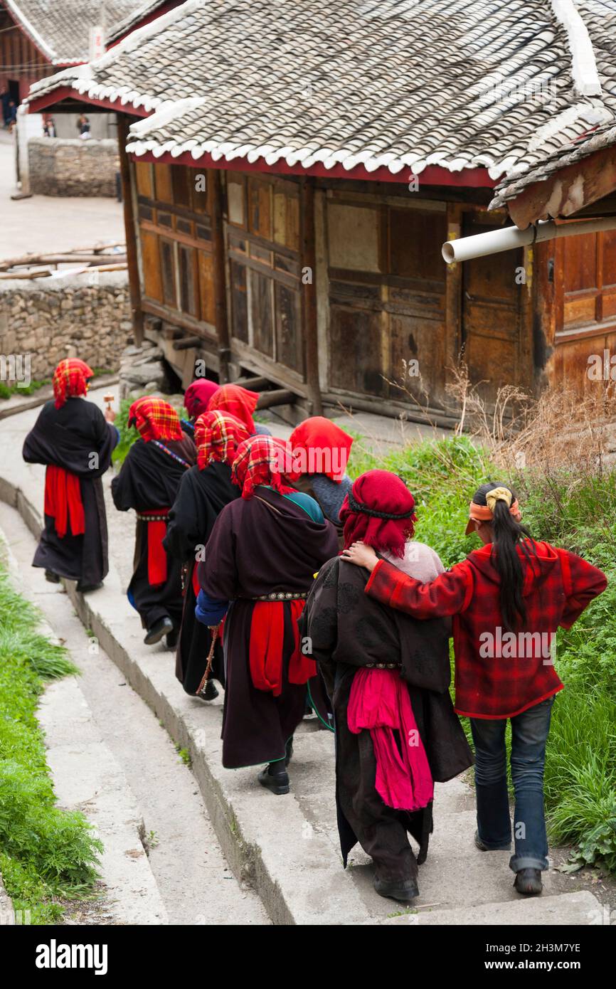 Un gruppo di adoratori buddisti cammina un sentiero / percorso da un piccolo tempio sopra la città; donne tibetane / donne etniche del Tibet, residenti o locali alla città cinese murata (antica città murata) di Songpan nel nord di Sichuan, Cina. Nel buddismo una donna può essere una suora. (125) Foto Stock