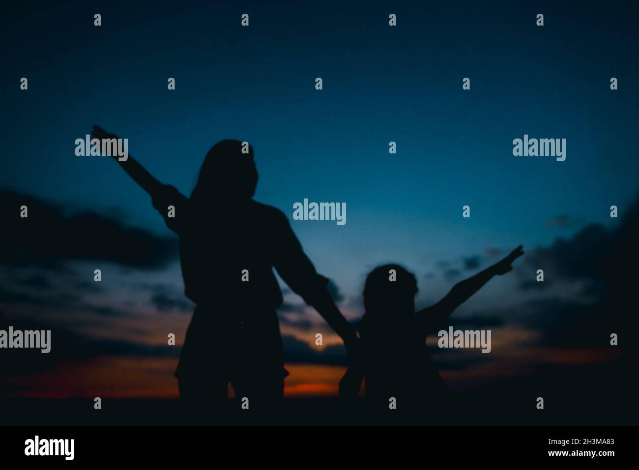 Black silhouette di donna e bambina camminando in vening, tramonto sullo sfondo. Foto Stock