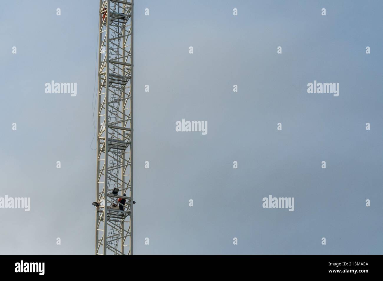 Al termine di un turno, due operatori di gru a torre scendono lungo le scale del montante. Foto Stock