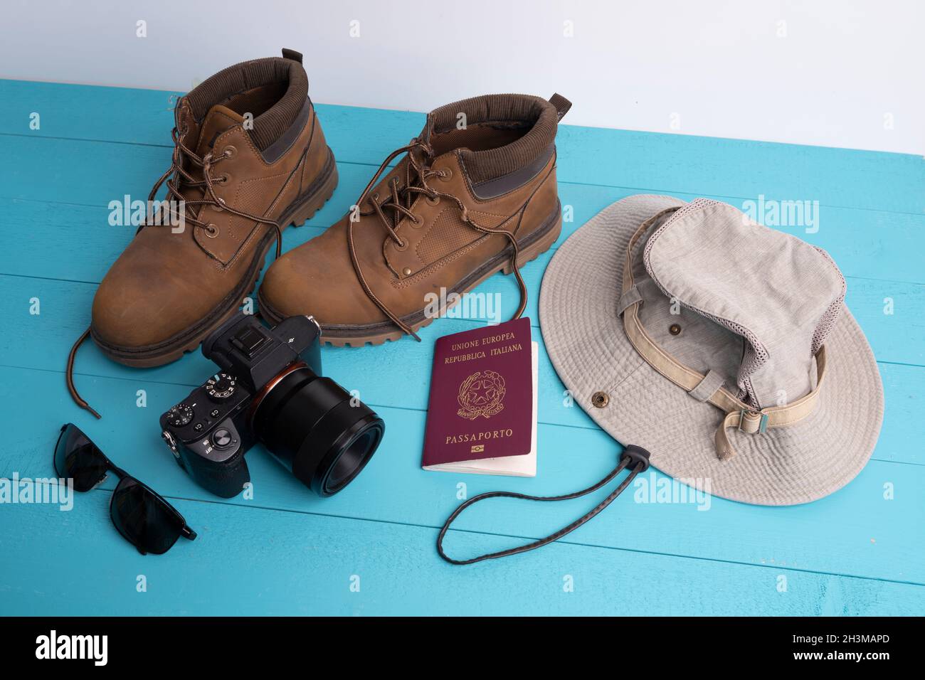 Una macchina fotografica, un cappello e un paio di scarpe su una superficie colorata Foto Stock