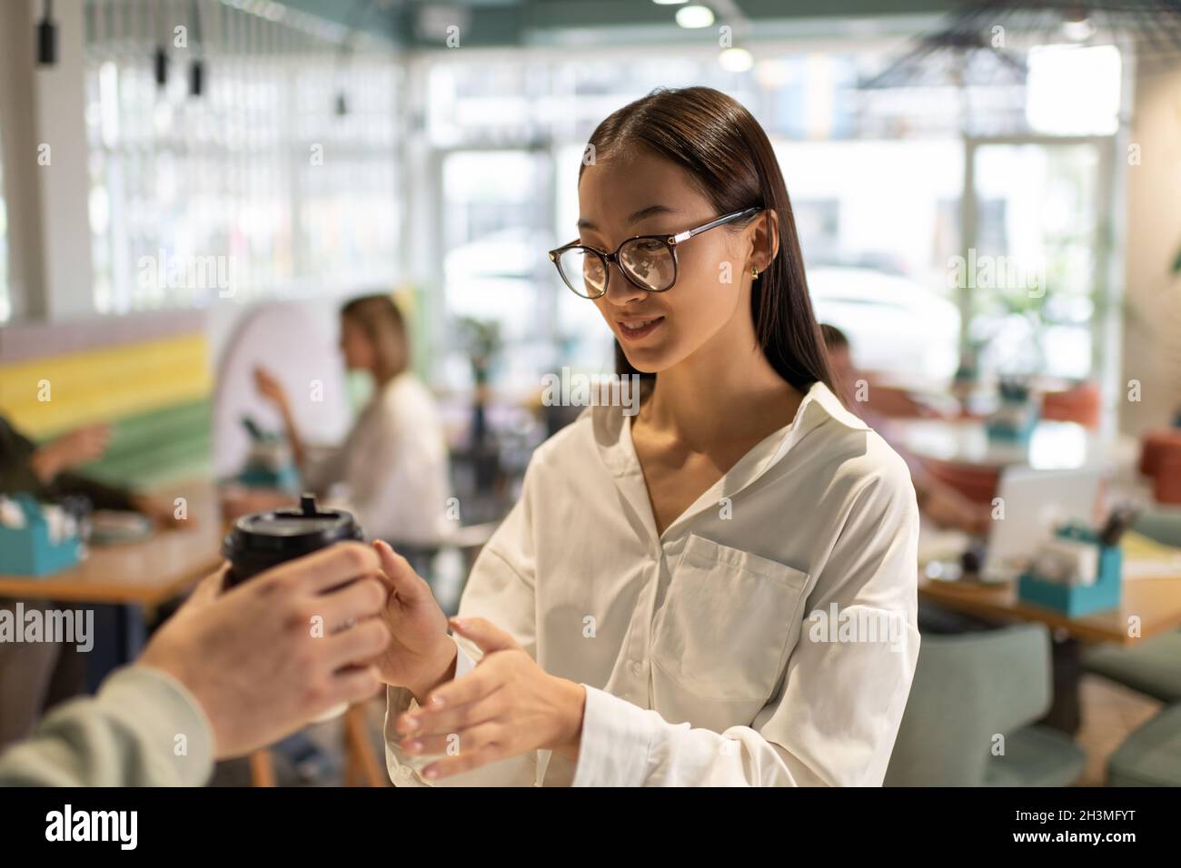 Donna asiatica felice in bicchieri che prendono la bevanda calda per andare dal barista in caffetteria Foto Stock