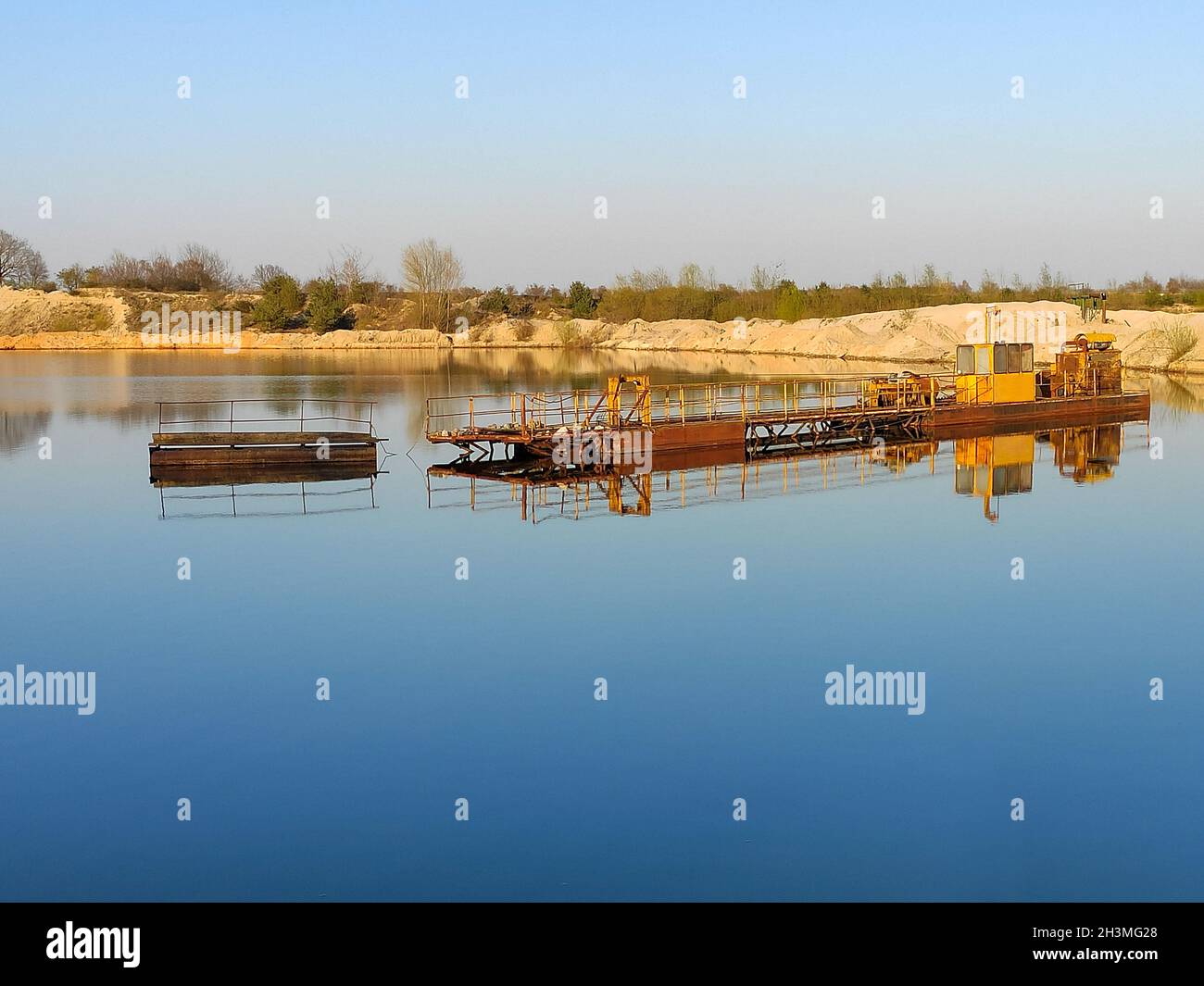 Macchina di scavo per lavori di movimento terra in cava di sabbia. Estrazione di sabbia da un lago. Foto Stock