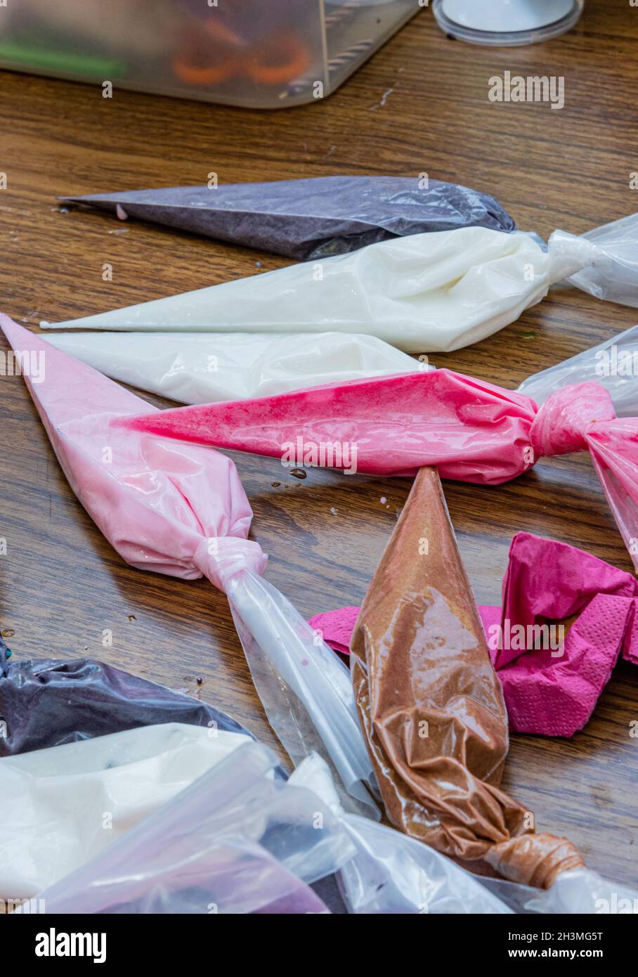 Vista dei sacchetti di tubatura con gli accoppiatori e le punte riempite con glassa reale per decorare i biscotti di zucchero. Foto di alta qualità Foto Stock