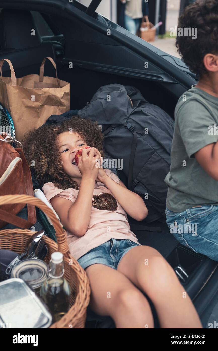 Vista ad angolo alto della ragazza che mangia mela dal fratello nel tronco dell'automobile Foto Stock