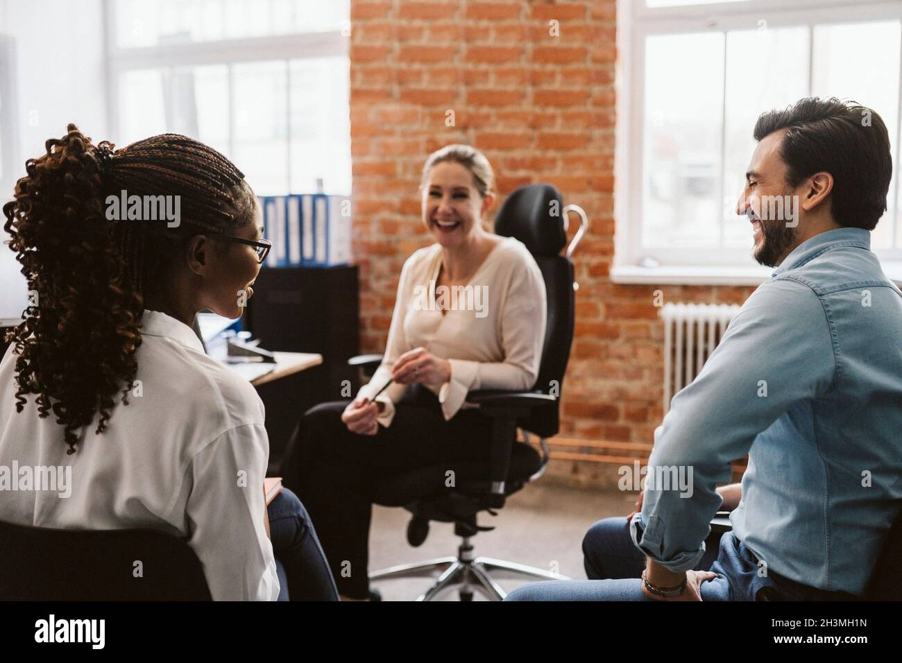 I professionisti femminili e maschili ridono mentre discutono in ufficio Foto Stock