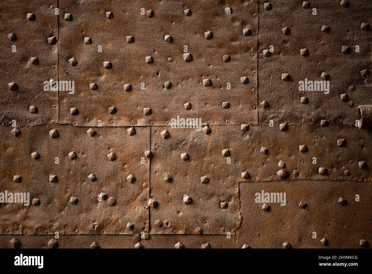 Vecchia parete coperta con fogli di ferro arrugginito con rivetti. Sfondo retrò astratto Foto Stock