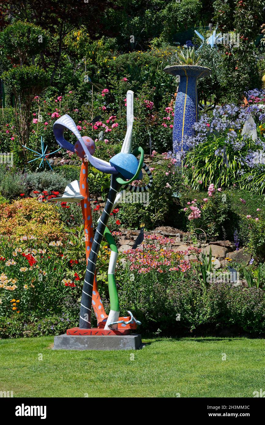 scena giardino; scultura whimsical; fiori; erba; arbusti, Colorato; alta urna a mosaico, The Giants House, South Island, Akaroa; Nuova Zelanda Foto Stock