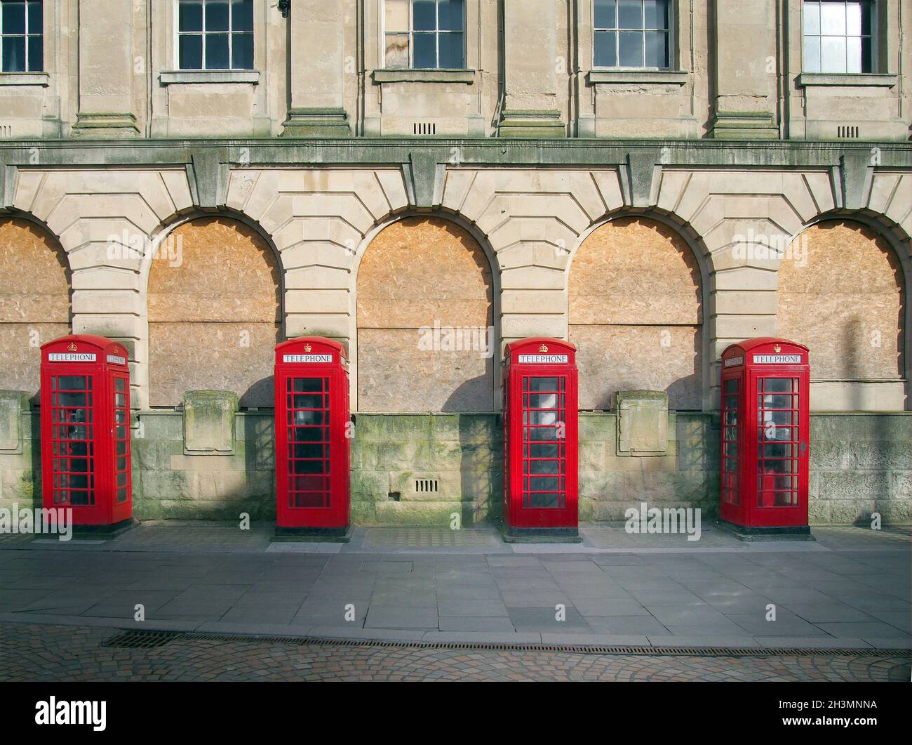 Una linea di quattro tradizionali scatole telefoniche rosse britanniche fuori da un vecchio edificio di uffici postali abbandonati a blackpool inghilterra Foto Stock