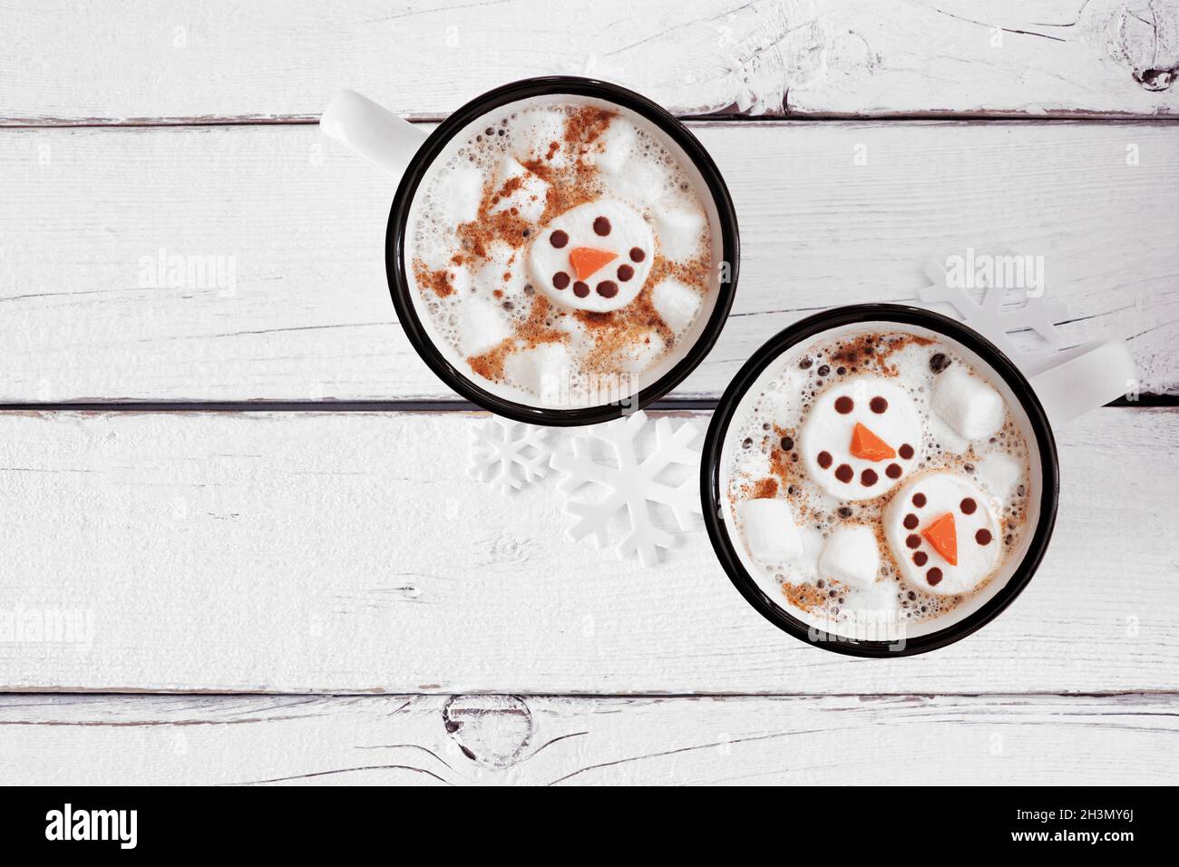 Due tazze di cioccolata calda per le vacanze con marshmallow da neve. Vista dall'alto su sfondo di legno bianco. Foto Stock