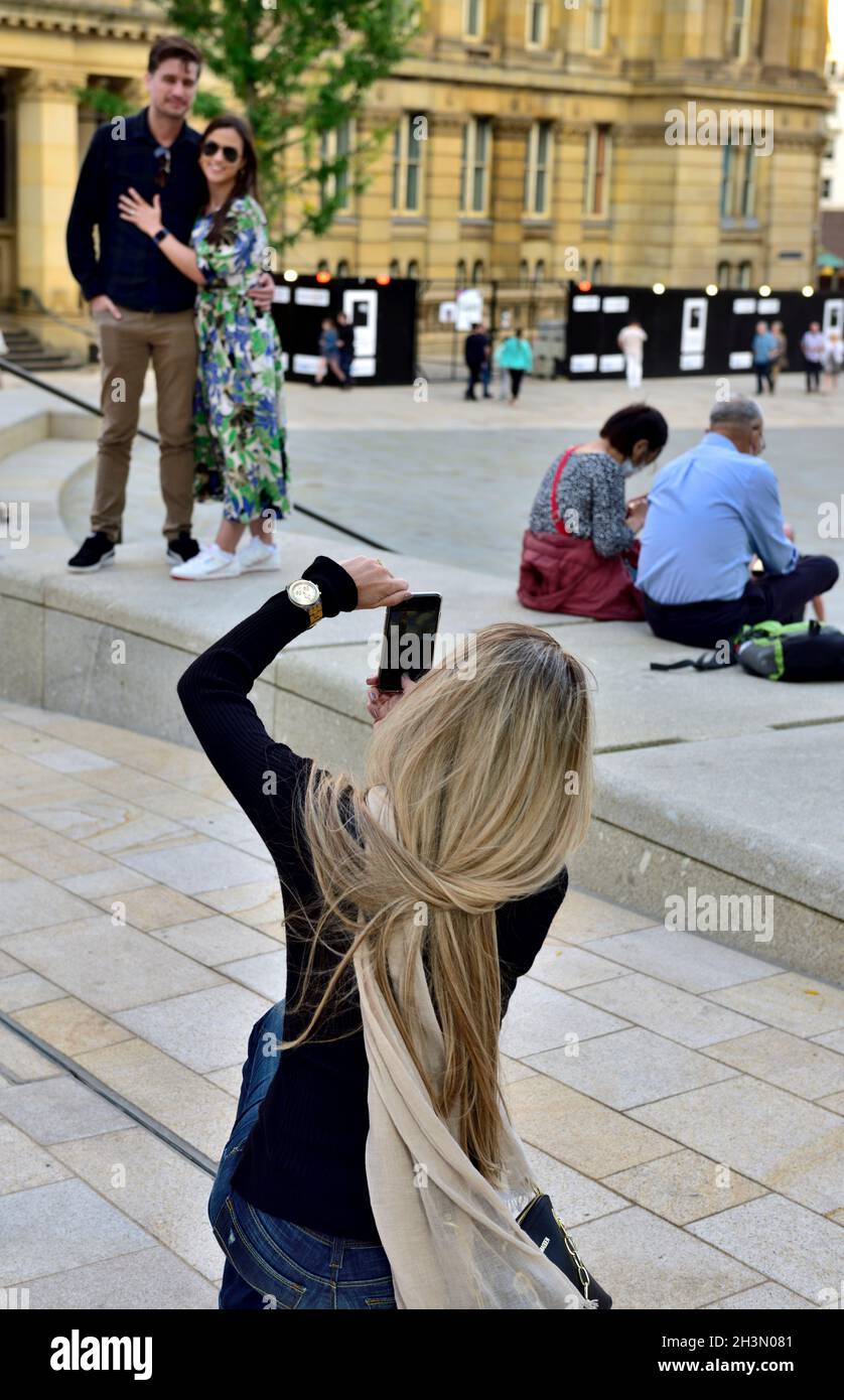 Donna bionda capelli fotografando gli amici con fotocamera telefono Foto Stock