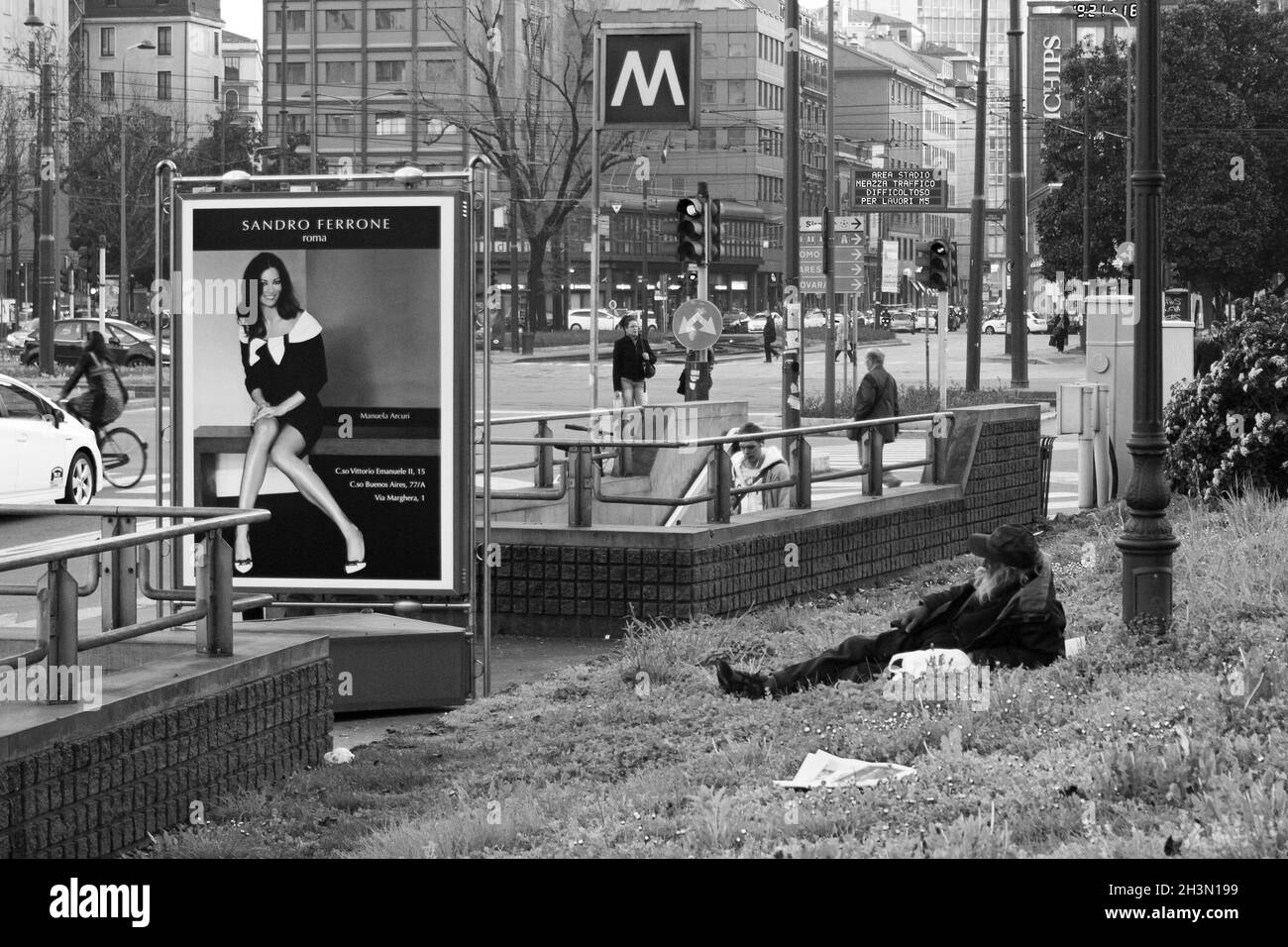 Milano, Italia; 23 marzo 2011: Senzatetto giacente accanto ad una pubblicità di beni di lusso. Foto Stock