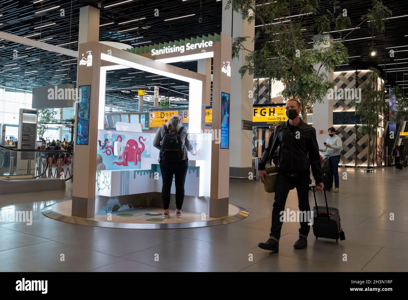 Un passeggero utilizza un punto di servizio di sanificazione presso l'aeroporto Schiphol di Amsterdam, Paesi Bassi. Le nuove stazioni igieniche consentono ai passeggeri di sanificare questo ettaro Foto Stock