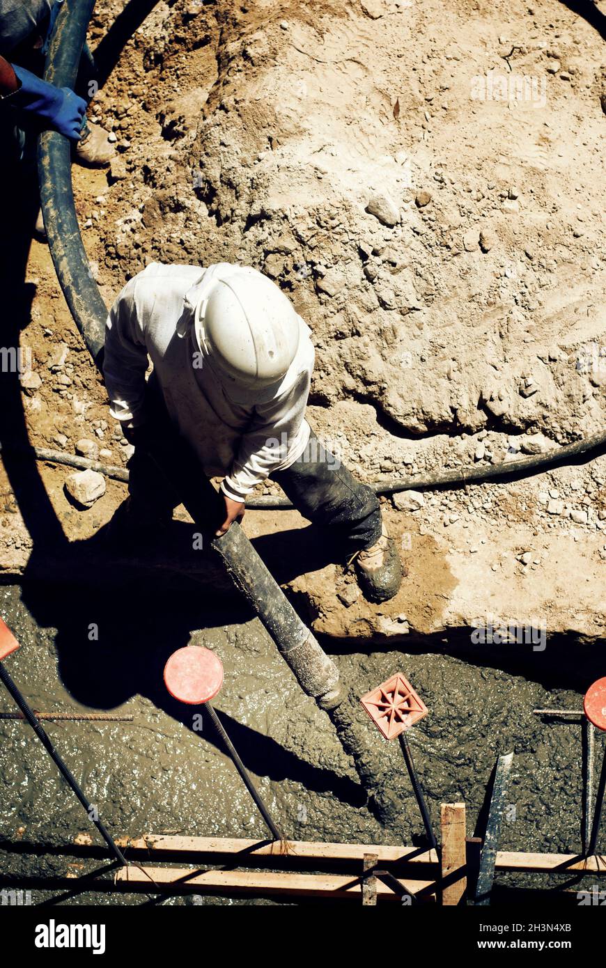 Lavoratore di costruzione che spara calcestruzzo in un muro di base strutturale Foto Stock