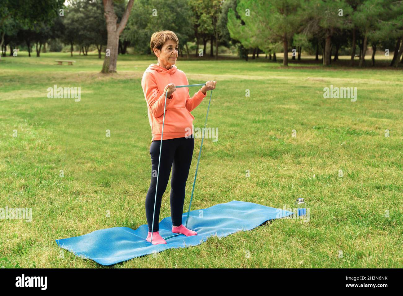 Donna anziana che fa pilates allenamento routine all'aperto al parco della città - Focus on Face Foto Stock