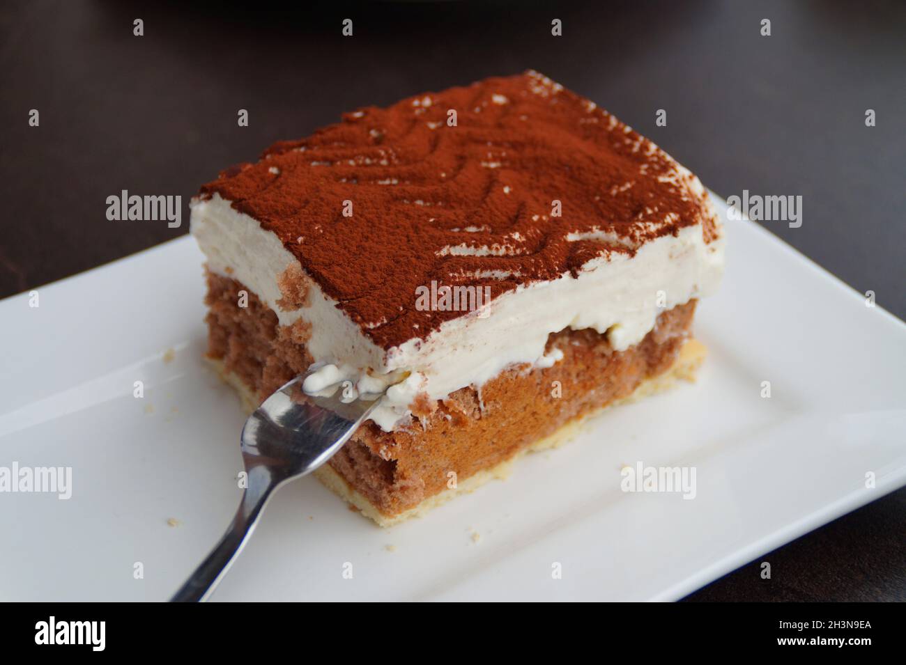Un delizioso pezzo di torta italiana tiramisù su un piatto quadrato Foto Stock
