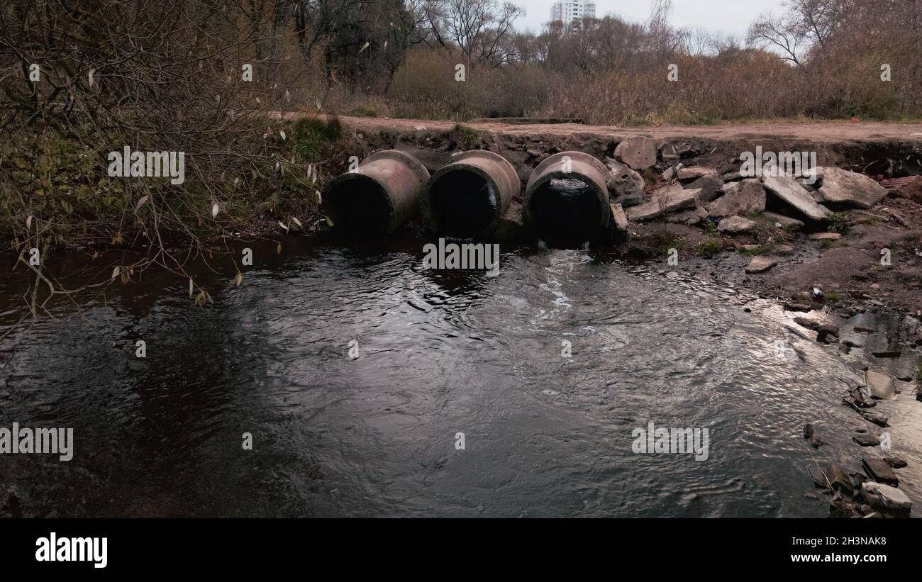 Tubi per rifiuti in calcestruzzo. Flussi di acqua fluiscono attraverso tubi di calcestruzzo. Corpo inquinato di acqua nel parco. Tiro dal drone. Fotografia aerea. Foto Stock