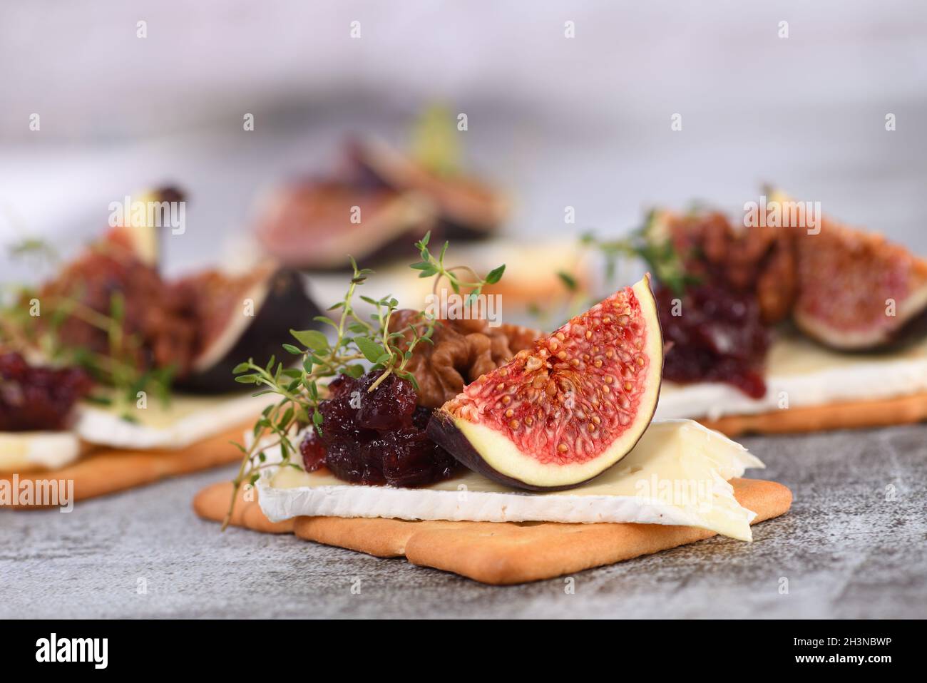 Cracker con una fetta di camembert, marmellata, fichi e noci. Un'ottima idea di snack per una vacanza, picnic o p Foto Stock