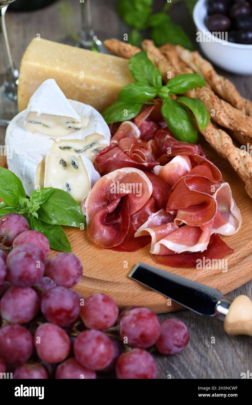 Antipasto. Spuntini a base di vino al prosciutto, formaggio brie con muffa, parmigiano con grissini, olive e p. Foto Stock