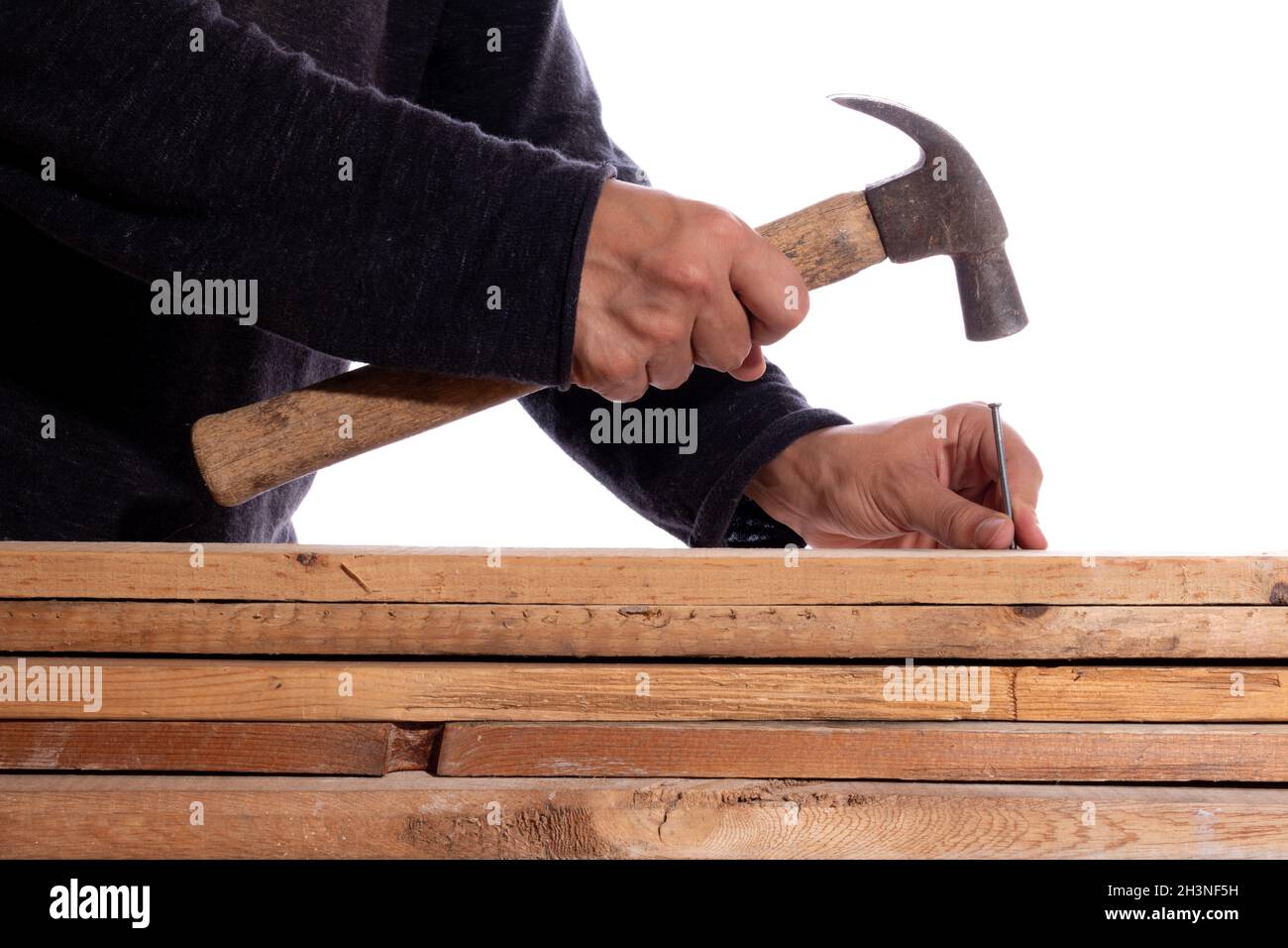 Uomo martellante chiodi in legno, isolato su sfondo bianco. Uomo sconosciuto in lavori di carpenteria. Foto Stock