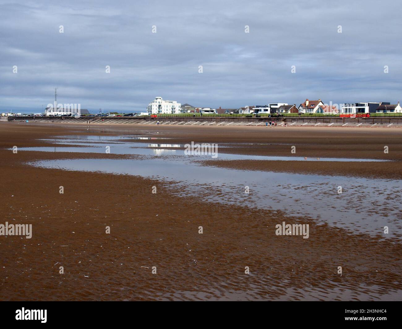 Persone che camminano sulla spiaggia a blundell Sands a crosby vicino southport merseyside con edificio e liverpool banchine in dista Foto Stock