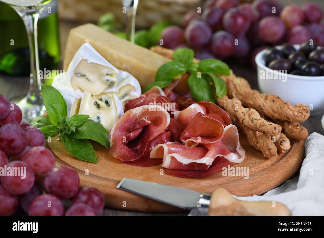 Antipasto. Spuntini a base di vino di prosciutto secco, formaggio camembert con muffa, parmigiano con grissini, olive Foto Stock