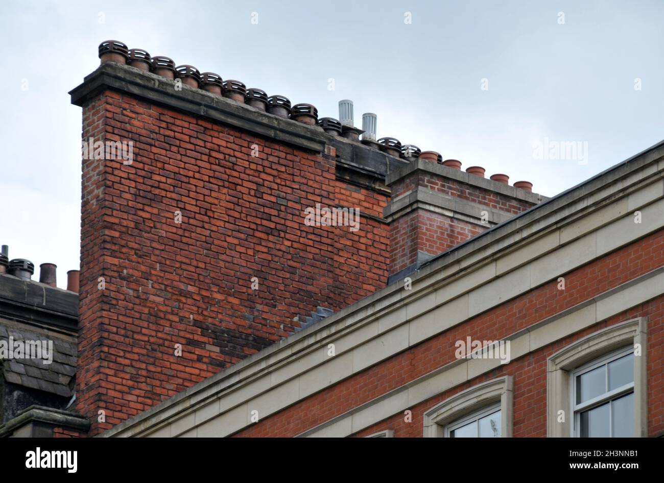 Una grande fila di tradizionali pentole di creta vecchio stile su un supporto di mattoni rossi contro un cielo grigio da quando edifici dove b Foto Stock