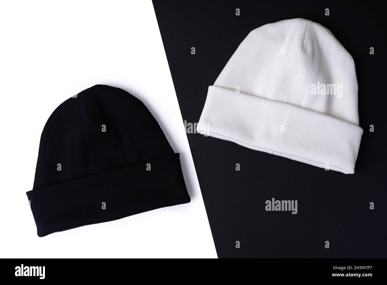 Due eleganti cappelli in stile beanie in bianco e nero su sfondo bianco e nero. Vista dall'alto Foto Stock