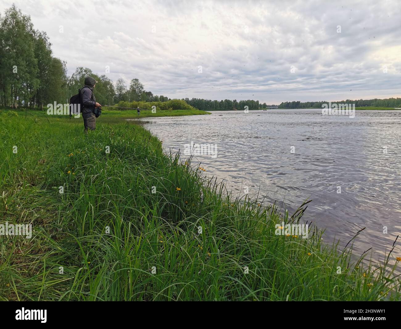 Un uomo che cattura il pesce di fronte ad un fiume in Finlandia. Foto Stock