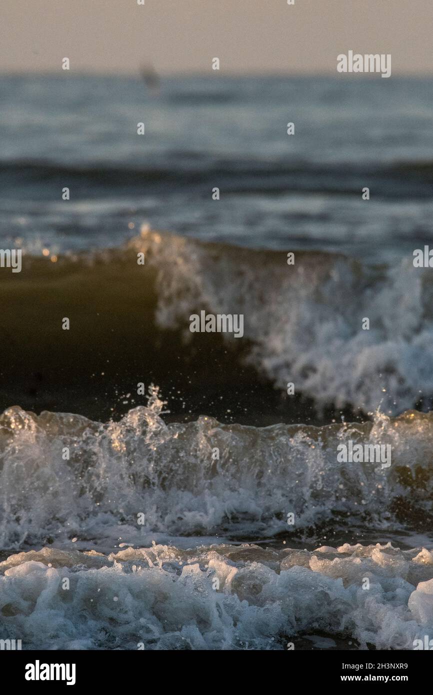 Sole baciato onde che arrivano a West Runton Beach, Norfolk Foto Stock