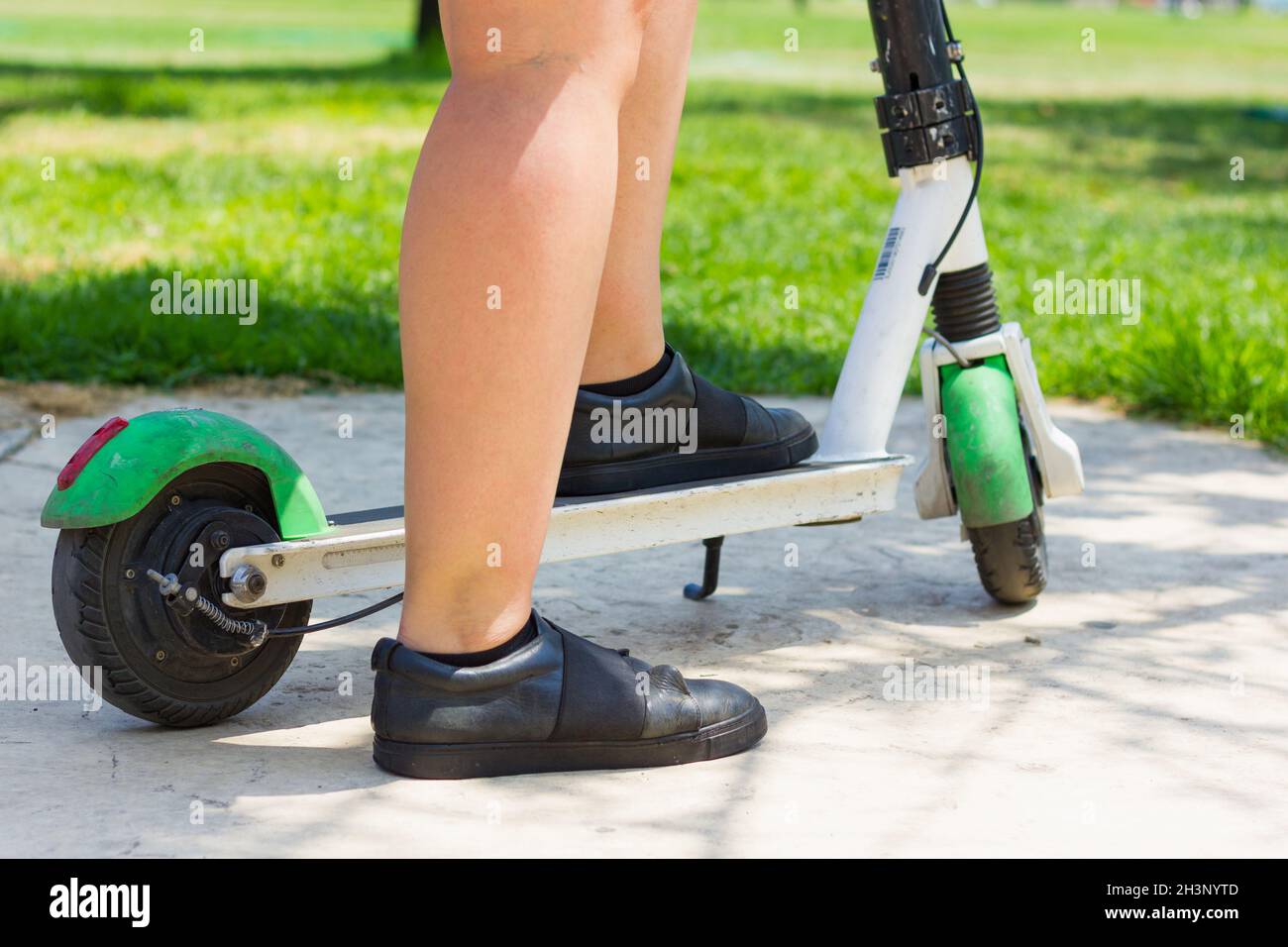 Piede di donna che salta su scooter elettrico. Trasporto ecologico della città, futuro, concetti alternativi di pendolarismo Foto Stock