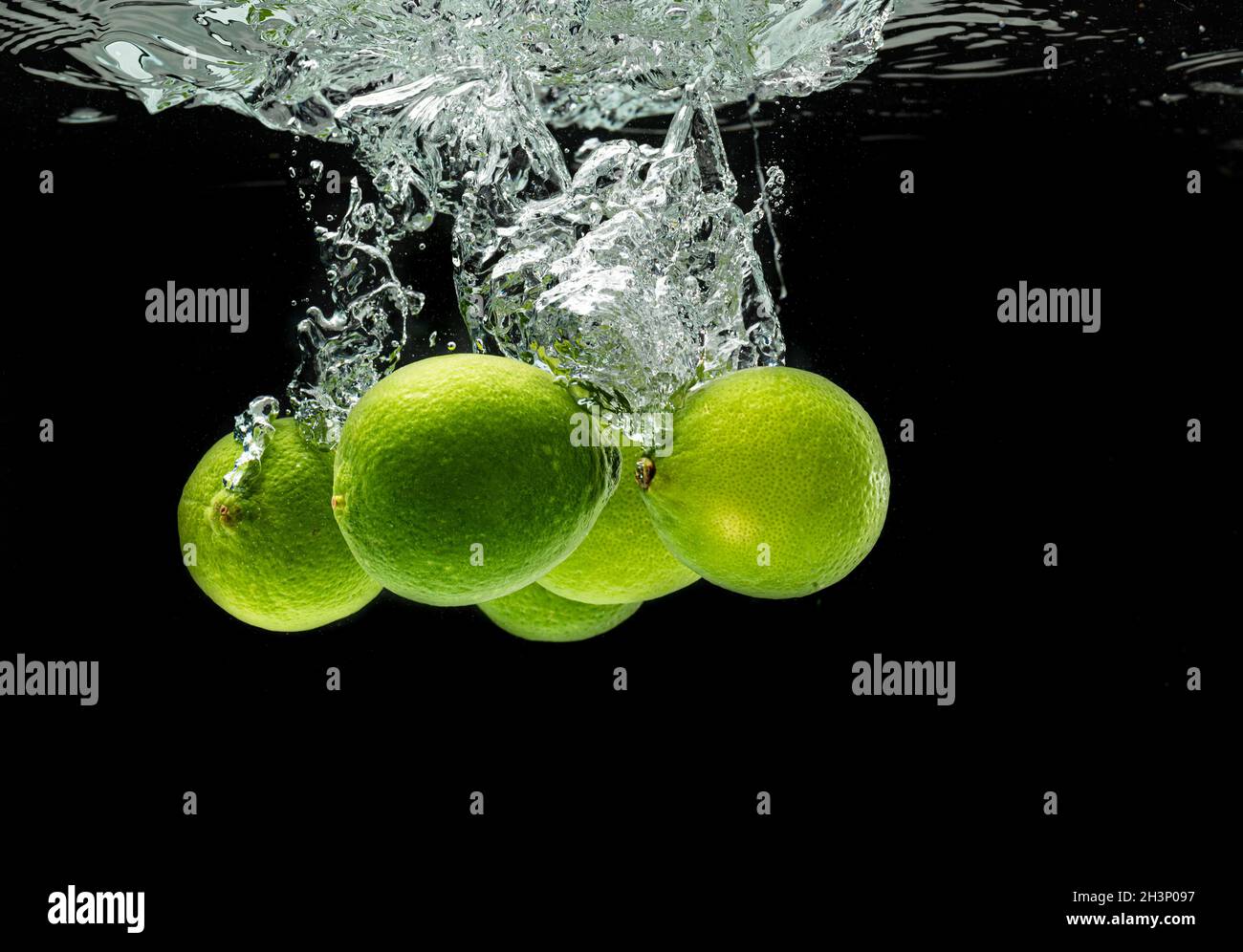 Citrus di lime spruzzi con le bolle in acqua isolato contro sfondo nero Foto Stock