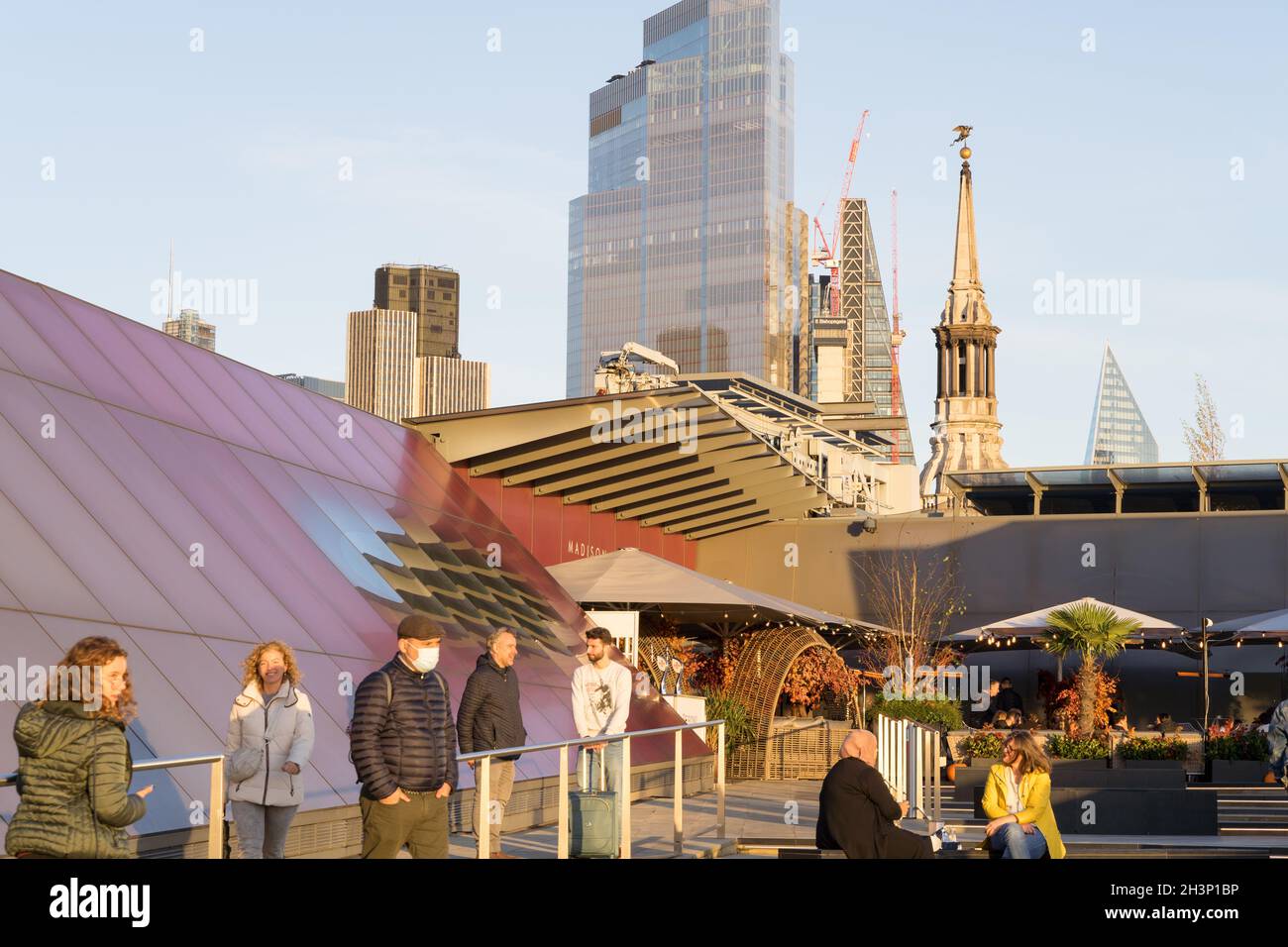 Gli uomini e le donne con maschera facciale godono del tramonto d'inverno sul giardino sul tetto che guarda il grattacielo in City of London Square Mile Inghilterra UK Foto Stock