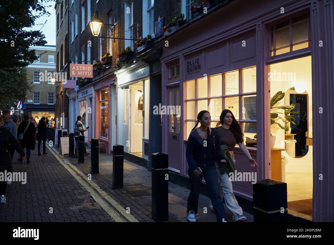 Londra, UK, 29 ottobre 2021: Mentre il crepuscolo cade a Covent Garden e nelle strade acciottolate circostanti, i turisti e gli amanti dello shopping godono di un incantesimo secco tra le docce a pioggia. Le campagne pubblicitarie volte a incoraggiare le persone a visitare Londra sembrano aver attirato molte visite familiari a metà termine e Londra ha attualmente un tasso di infezioni da covid inferiore rispetto ad altre aree del paese. Le decorazioni natalizie sono già in alto nella zona centrale del mercato. Anna Watson/Alamy Live News Foto Stock