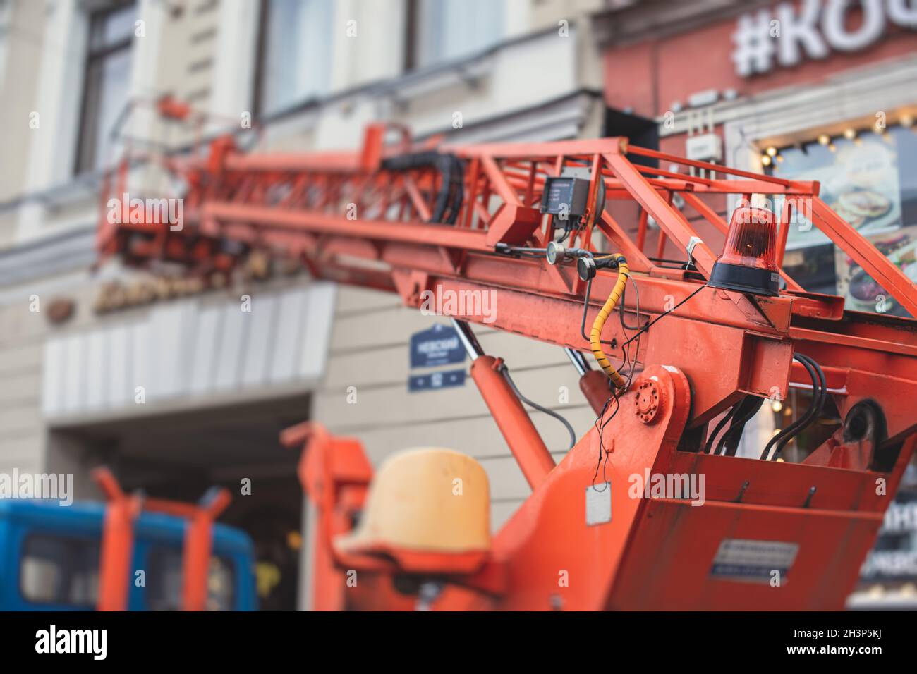 Piattaforma di lavoro aerea veicolo durante la decorazione della facciata, ascensore telescopico arancione sul cantiere, noleggio AWP lavoro nelle strade della città, motore Foto Stock