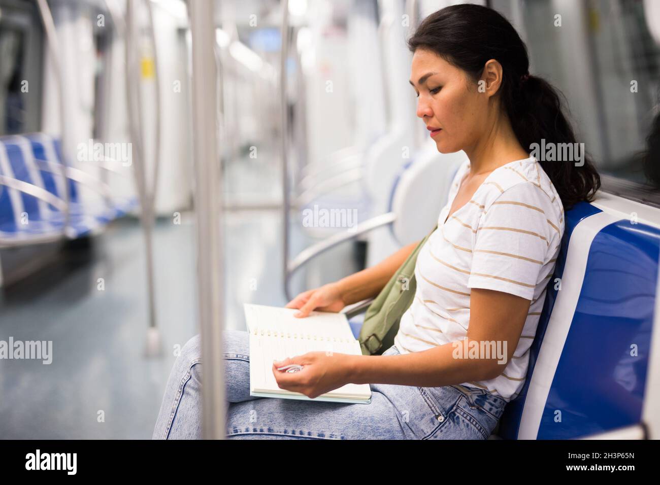 Donna che legge libro in metropolitana treno Foto Stock