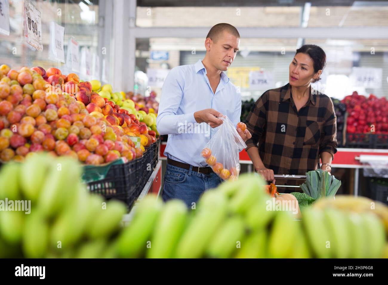 Coppia di famiglia in cerca di frutta e verdura in fruttivendolo Foto Stock
