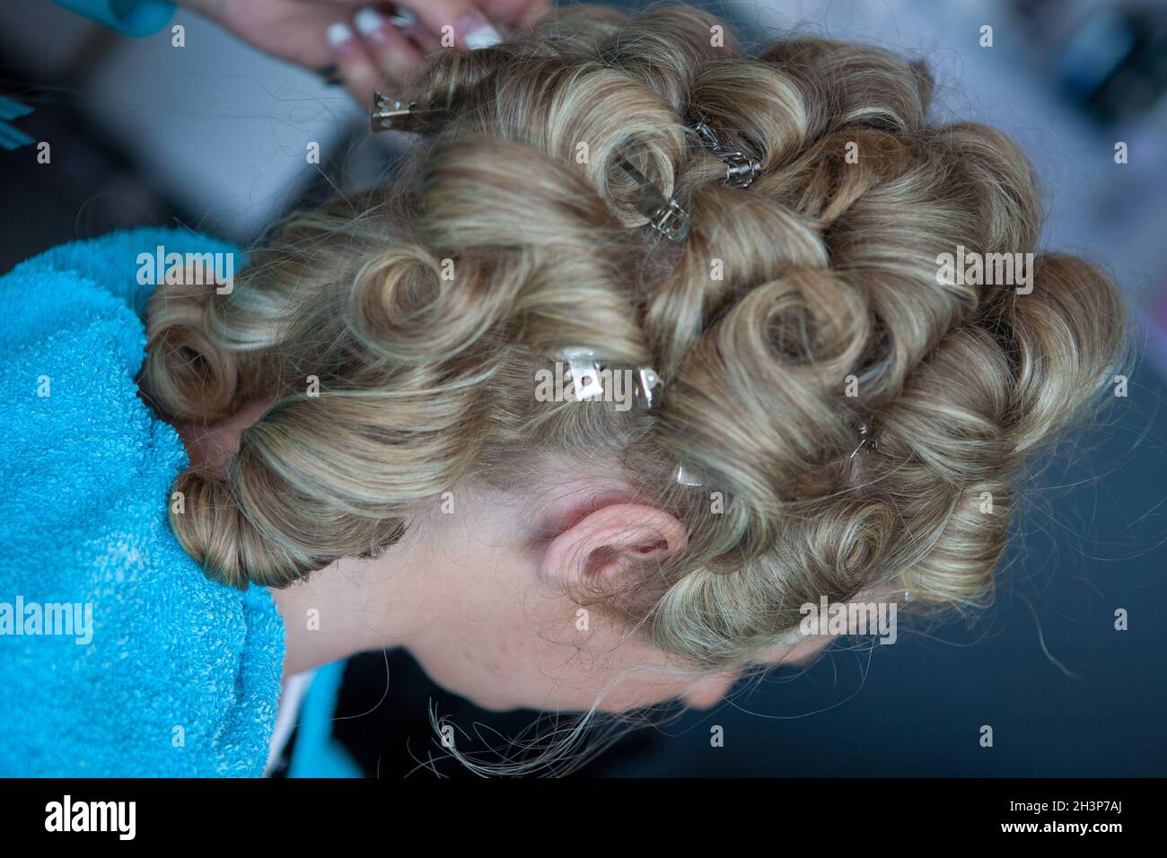 Primo piano di parrucchiere professionale al salone di bellezza, arricciando i capelli femminili Foto Stock