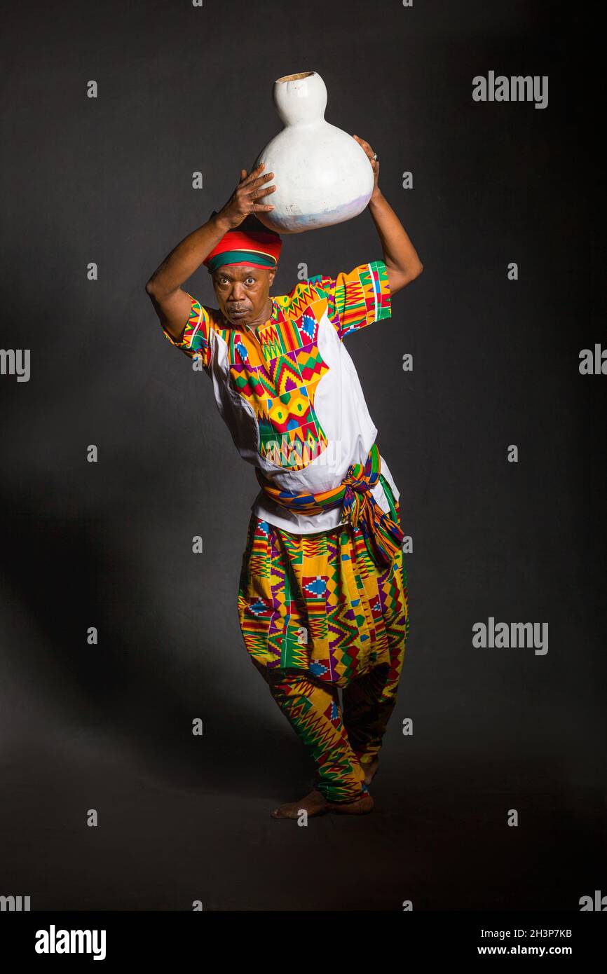 Uomo africano in abiti tradizionali sorriso toothy, su sfondo grigio Foto Stock
