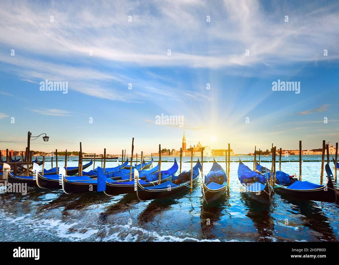 Gondole parcheggiate in Piazza San Marco e l'argine del Palazzo Ducale e il sole del tramonto (Venezia, Italia) Foto Stock