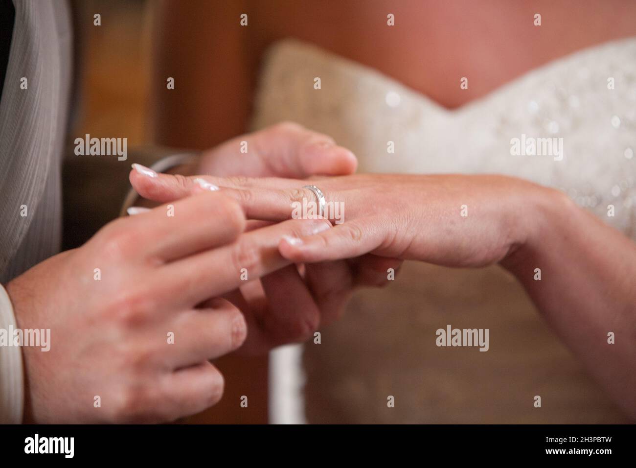 Primo piano della sposa di mettere un anello di nozze su govern dito. Giovane scambiare gli anelli di nozze. Foto Stock