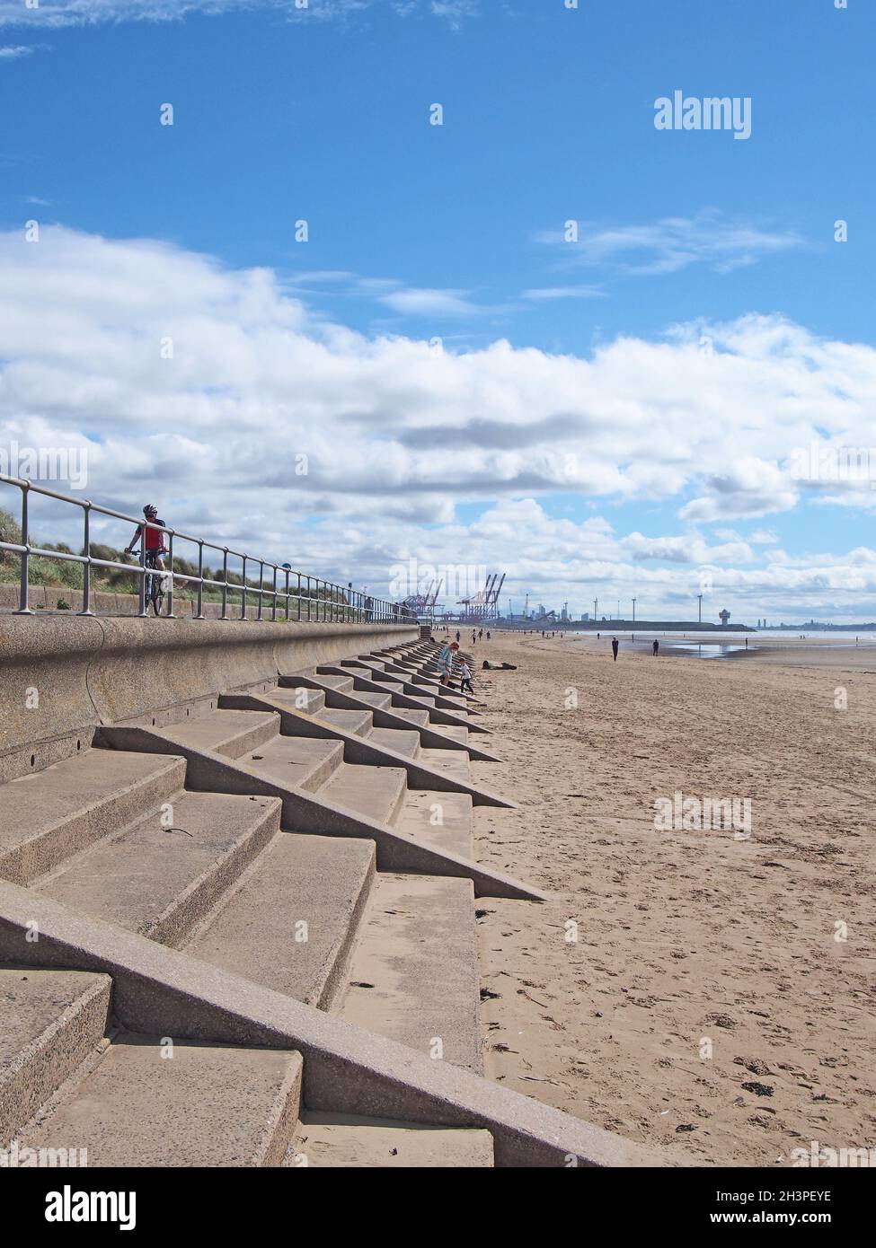 Persone sulla spiaggia a blundell sabbie a crosby vicino southport merseyside con ringhiere fronte mare e Liverpool molo visibile in Foto Stock