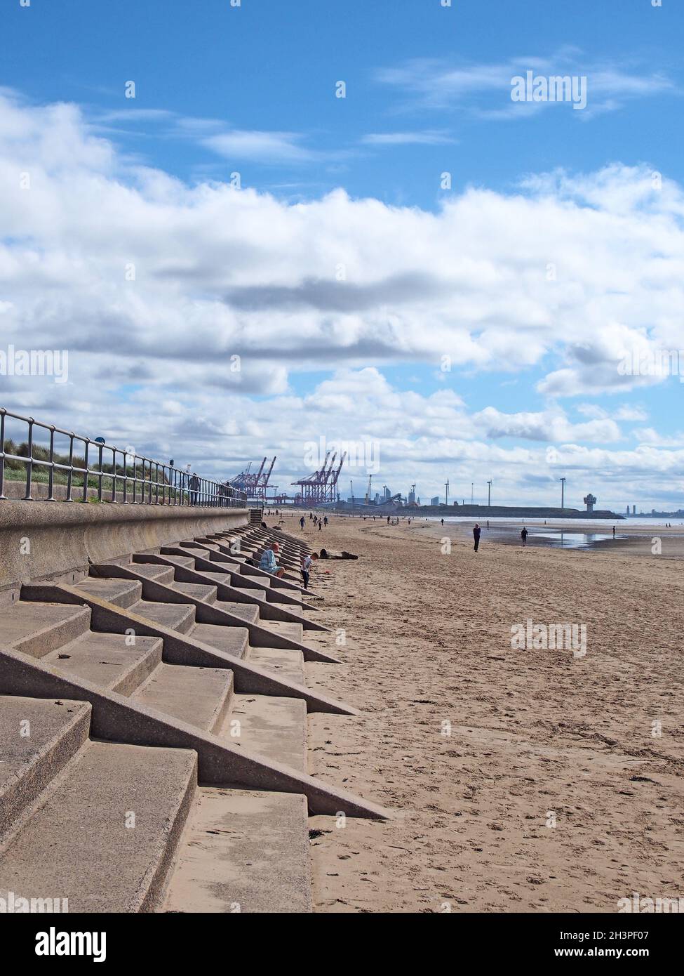 Persone sulla spiaggia a blundell sabbie a crosby vicino southport merseyside con ringhiere fronte mare e Liverpool molo visibile in Foto Stock
